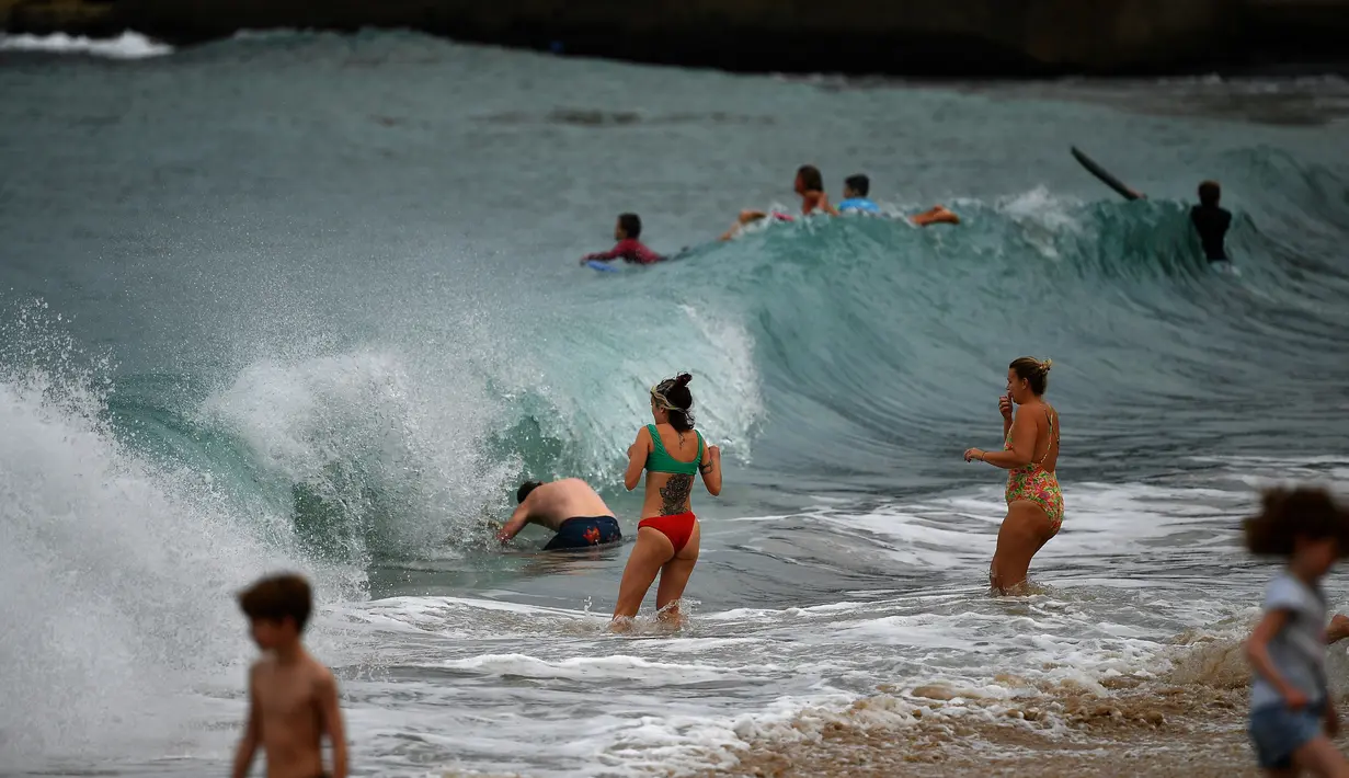 Orang-orang bermain di Pantai Maroubra yang dibuka kembali untuk aktivitas warga di tengah pembatasan sosial yang diberlakukan di kala wabah corona (Covid-19) di Sydney, Australia (20/4/2020). (AFP/Saeed Khan)