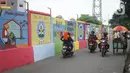 Pengguna jalan melintas di depan mural bertema Kota Jakarta di sekitar Rusunawa KS Tubun, Jakarta, Senin (23/11/2020). Mural tersebut dibuat guna memercantik lingkungan di sekitar rusun agar lebih berwarna dan tidak tampak kumuh. (Liputan6.com/Immanuel Antonius)