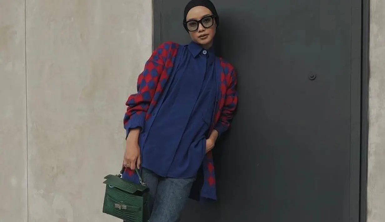 Cocok untuk outfit ke kantor, padukan kemeja warna biru dongker dengan cardigan nuansa pink-biru dongker. Untuk hijab, pilihlah warna netral seperti hitam. Sementara untuk bawahan, kamu bisa memilih celana jeans seperti fashion blogger Vira Tandia satu ini. (Instagram/viratandia).