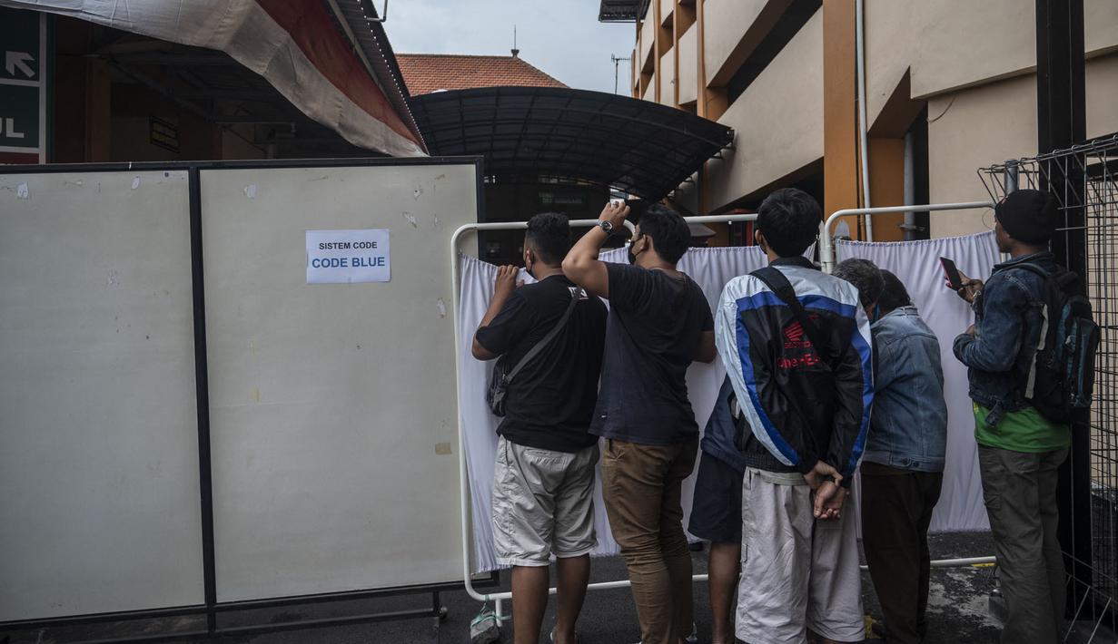 Keluarga dan kerabat korban tragedi Stadion Kanjuruhan menunggu di luar sebuah rumah sakit di Malang, Jawa Timur pada 2 Oktober 2022. Sedikitnya 174 orang tewas di stadion sepak bola Indonesia ketika ribuan penggemar tuan rumah yang marah menyerbu lapangan dan polisi menanggapi dengan gas air mata yang memicu desak-desakan, kata pihak berwenang pada 2 Oktober. (AFP/Juni Kriswanto)