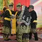 Bupati Bengkalis Amril Mukminin (dipakaikan selempang) ketika menerima gelar adat dari LAM Kabupaten Bengkalis. (Liputan6.com/Istimewa/M Syukur)