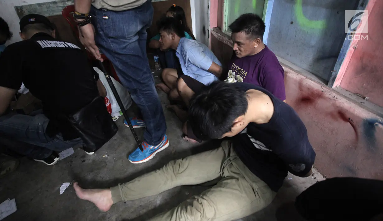 Sejumlah tersangka tertunduk lesu usai polisi menggerebek peredaran narkoba di kawasan Kampung Ambon, Cengkareng, Jakarta Barat, Rabu (24/1). Penggerebekan dilakukan oleh 150 personel gabungan dari Brimob dan TNI. (Liputan6.com/Arya Manggala)