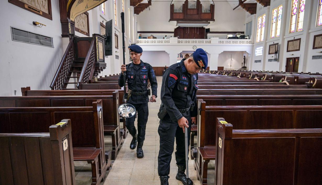 Menggunakan alat metal detektor, personel dari unit Gegana dan Jihandak Brimob Polda Jawa Timur melakukan penyisiran setiap area untuk memastikan keamanan guna kelancaran ibadah Natal. Tampak dalam foto, personel dari unit Gegana dan Jihandak Brimob Polda Jawa Timur melakukan pemeriksaan di dalam area Gereja Katedral Hati Kudus Yesus, atau yang dikenal secara lokal sebagai gereja "Hati Kudus Yesus", Surabaya, pada Rabu 24 Desember 2025. (JUNI KRISWANTO/AFP)