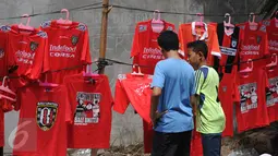 Beberapa suporter memilih kaos tim yang dijajakan di luar Stadion Dipta, Gianyar, Bali, Minggu (30/8/2015). Jelang pembukaan turnamen Piala Presiden 2015, Stadion Kapten I Wayan Dipta dijaga ratusan personel keamanan. (Liputan6.com/Helmi Fithriansyah)
