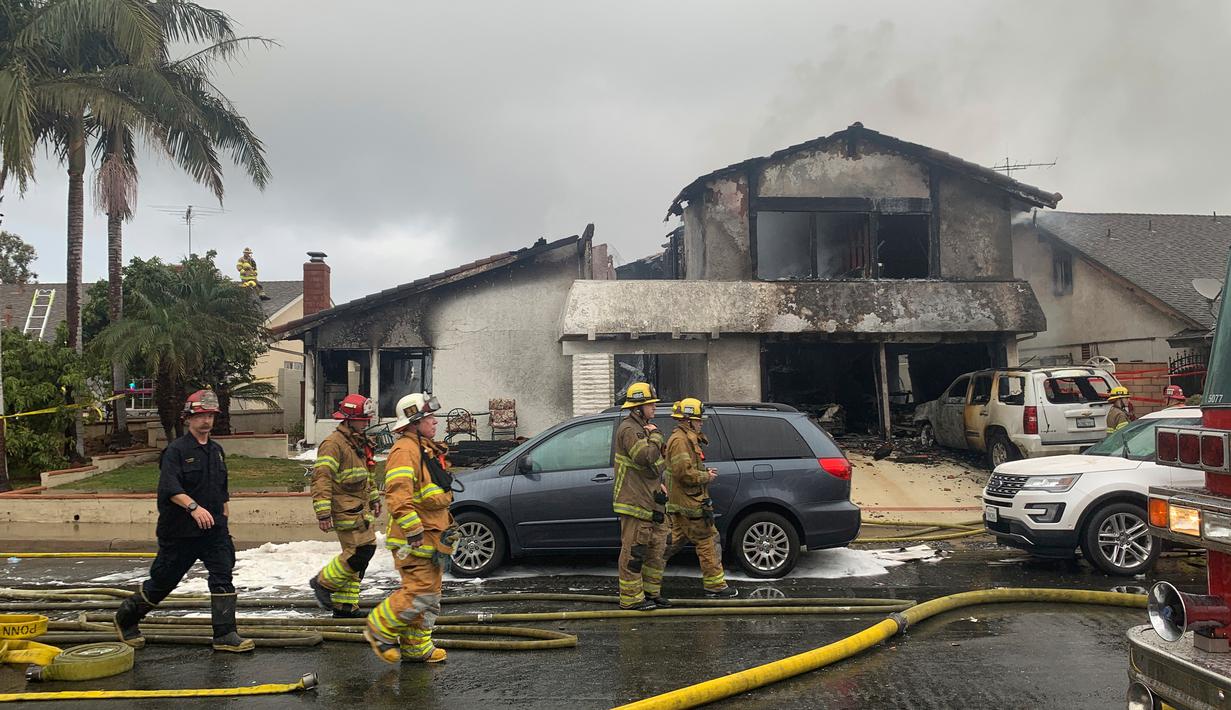 Petugas pemadam kebakaran usai memadamkan api di lokasi kecelakaan pesawat di sebuah rumah di Yorba Linda, California (3/2). Pesawat Cessna 414A jatuh di Yorba Linda tak lama setelah lepas landas dari Bandara Fullerton Municipal. (AP Photo/Alex Gallardo)