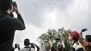 Warga menyaksikan manuver pesawat tempur TNI AU saat perayaan HUT ke-77 Republik Indonesia (RI) di Taman Aspirasi Monumen Nasional (Monas), Jakarta Pusat, Rabu (17/8/2022). Aksi akrobatik pesawat tempur dan helikopter yang membawa bendera Merah Putih tersebut disambut antusias oleh warga yang datang untuk mengikuti upacara Kemerdekaan RI. (merdeka.com/Iqbal S Nugroho)