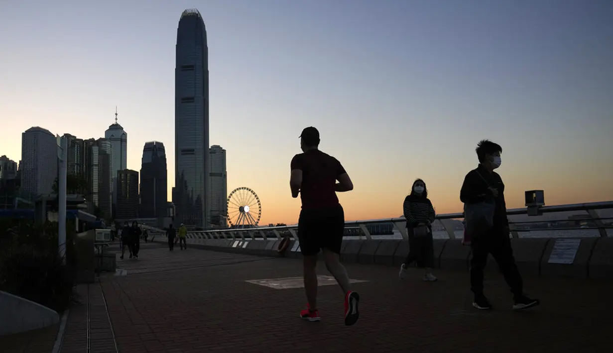 Orang-orang joging dan berjalan di sepanjang tepi pantai di Hong Kong, 8 Maret 2022. Pemerintah Hong Kong memperluas langkah-langkah jarak sosial, memaksa banyak fasilitas bisnis dalam ruangan seperti pusat kebugaran, salon, bar, dan spa tutup. (AP Photo/Kin Cheung)