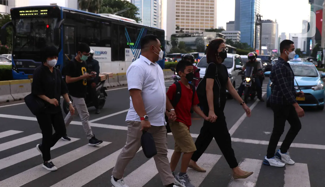 Warga melintas di kawasan Bundaran HI, Jakarta, Jumat (31/12/2021). Polda Metro Jaya melarang perayaan malam tahun baru 2022 di seluruh wilayah DKI Jakarta. Kebijakan itu berlaku mulai 31 Desember 2021 hingga 2 Januari 2022. (Liputan6.com/Angga Yuniar)