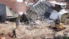 Petugas berada dekat rumah yang hancur tertimpa tanah longsor di Perumahan Nerada Estate Ciputat, Tangerang Selatan, Sabtu (12/6/2021). Tidak ada korban jiwa dalam peristiwa longsor yang menimpa sejumlah rumah akibat hujan deras yang terus menerus di kawasan tersebut. (Liputan6.com/Angga Yuniar)