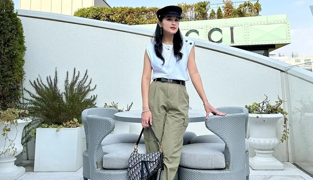 Gaya OOTD Sandra Dewi dengan busana tanpa lengan lengkap dengan topi dan hand bag dari brand ternama ini pun tak luput dari sorotan. Dirinya tampil menawan dalam busana kasual serta makeup natural. (Liputan6.com/IG/@sandradewi88)