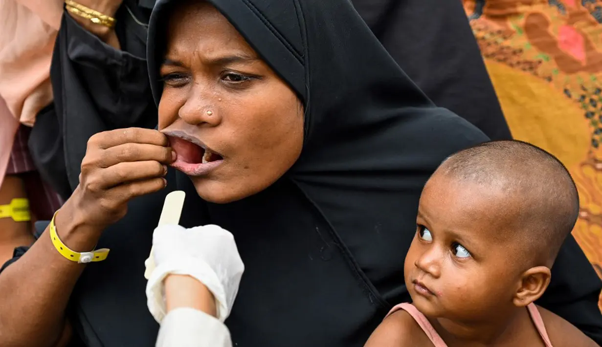 Petugas kesehatan Universitas Syiah Kuala memeriksa seorang pengungsi Rohingya di tempat penampungan sementara gedung pemerintah di Banda Aceh, Aceh, Kamis (11/1/2024). Tim medis dari Rumah Sakit Pendidikan Universitas Syiah Kuala Banda Aceh memberi pelayanan kesehatan rutin bagi pengungsi Rohingya di Banda Aceh. (CHAIDEER MAHYUDDIN/AFP)