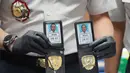 Dari penggeledahan, petugas menyita sejumlah barang bukti yang memperkuat dugaan adanya aktivitas cyber crime, di antaranya atribut yang menyerupai seragam dan tanda pengenal Kepolisian Jepang; puluhan unit telepon genggam dan perangkat komputer; perangkat penguat (booster) serta pengacak sinyal; serta berbagai perangkat elektronik pendukung lainnya. Tampak dalam foto, seorang petugas Imigrasi menunjukkan lencana polisi Jepang palsu yang disita dari warga negara Jepang yang diduga terlibat dalam sindikat penipuan daring (online), di Bogor, Jawa Barat, Rabu 4 Maret 2026. (AP Photo/Achmad Ibrahim)