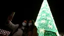 Sejumlah warga yang mengenakan masker berpose untuk difoto di bawah lampu-lampu Natal dan Tahun Baru pada masa pandemi COVID-19 di Kota Lisbon, Portugal, 17 Desember 2020. Warga Portugal tidak diizinkan meninggalkan rumah antara pukul 13.00 - 05.00 mulai 1 Januari - 3 Januari. (Xinhua/Pedro Fiuza)