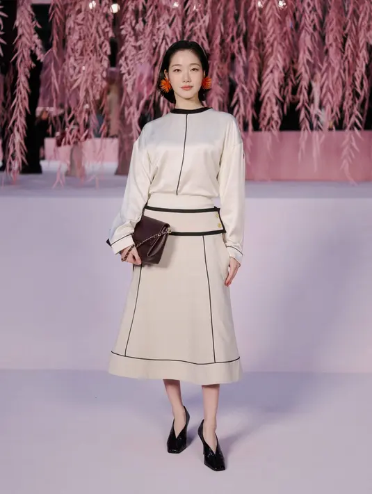 Kim Go Eun tampil feminin setelan long sleeve satin dan rok midi A-line dengan detail garis. Anting merah dengan aksen spike jadi aksesori yang statement [Chanel]