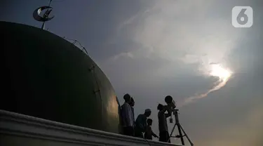 Petugas Masjid Al-Musyariin mengamati posisi hilal menggunakan teropong saat Rukyatul Hilal di Jakarta, Minggu (1/5/2022). Pemantauan hilal yang dilakukan menggunakan teropong tersebut memastikan Idul Fitri 1443 H jatuh pada 2 Mei 2022. (Liputan6.com/Faizal Fanani)