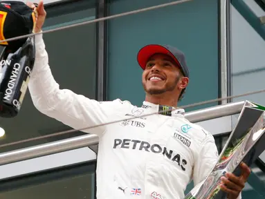 Pembalap Mercedes, Lewis Hamilton bersorak sambil memegang trofi Grand Prix (GP) China di Sirkuit Internasional Shanghai, Minggu (9/4). Hamilton finis pertama dengan catatan waktu 1 jam 37 menit 36,158 detik.(AP Photo/Toru Takahashi)