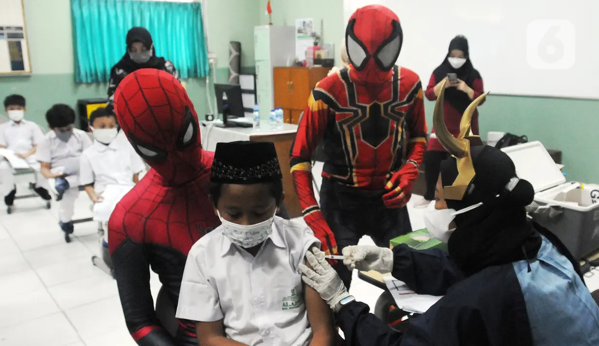 Murid SD dipangku Spiderman saat disuntik vaksin COVID-19 dosis kedua di Sekolah Al-Azhar, BSD, Tangerang Selatan, Banten, Senin (17/1/2022). Sebanyak 450 murid divaksin dengan melibatkan tokoh Spiderman untuk menghibur sekaligus menghilangkan rasa takut anak-anak. (merdeka.com/Arie Basuki)