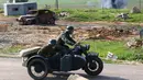 Adegan aktor sedang mengendarai motor lengkap dengan atribut tentara saat memainkan rekonstruksi pertempuran Perang Dunia II, di Memorial "Stalin Line", dekat Desa Goroshki, Belarusia, (10/9). (Reuters/Vasily Fedosenko)