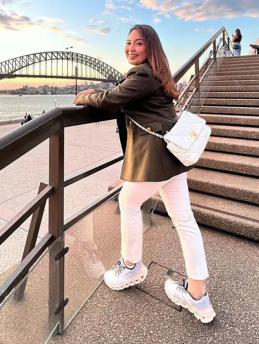 Angelica tampil dengan outer blazer kulit hitam dipadukan celana dan tas putih serasi dengan sneakersnya. [@angelicamanopo]
