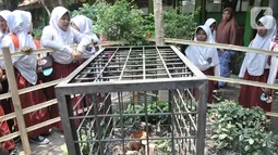 Siswa mengamati bunga bangkai jenis Amorphophallus Paeoniifolius di halaman SDN Kayuringin Jaya II, Bekasi, Jawa Barat, Selasa (8/10/2019). Bunga bangkai dengan tinggi 30 cm tersebut menjadi perhatian siswa dan warga sekitar karena baru pertama kali terjadi. (merdeka.com/Iqbal Nugroho)