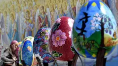Seorang wanita melihat telur Paskah besar yang dipajang di depan Katedral Mikhaylivsky di pusat Kiev sebelum perayaan Paskah, Ukraina, Rabu (12/4). Keberadaan telur Paskah besar ini menjadi daya tarik bagi wisatawan. (AFP PHOTO / Sergei SUPINSKY)