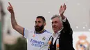 <p>Pelatih Real Madrid, Carlo Ancelotti dan penyerang Karim Benzema melambai kepada suporter saat merayakan trofi La Liga Spanyol di alun-alun Plaza Cibeles di Madrid pada 30 April 2022. Real Madrid mengamankan gelar La Liga ke-35  setelah kemenangan kandang 4-0 atas Espanyol. (AFP/Oscar Del Pozo)</p>