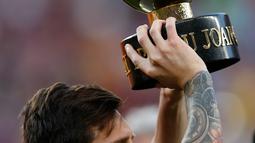 Penyerang Barcelona, Lionel Messi mengangkat Piala Joan Gamper usai pertandingan melawan Boca Juniors di stadion Camp Nou, Spanyol (15/8). Barcelona menang telak 3-0 atas Boca Juniors. (AP Photo/Manu Fernandez)