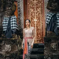 Anya terlihat anggun dalam balutan kebaya Bali berwarna cream. Kebaya tersebut ia padukan bersama obi berwarna pink salmon. Sementara untuk bawahan, Anya memilih kain songket berwarna hitam-emas. [@anyageraldine]