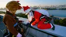 Dua petugas berkostum Santa Claus dan rusa bersiap turun untuk membersihkan kaca-kaca gedung bertingkat di pusat perbelanjaan di Tokyo, Jepang, Kamis (21/12). Para pekerja ini berbagi kecerian Natal dalam bentuk yang berbeda. (AP/Shizuo Kambayashi)