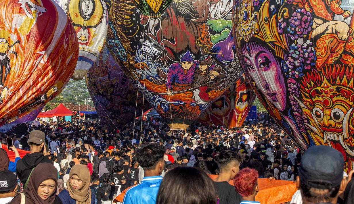 Balon-balon kertas berukuran raksasa dengan motif tradisional diterbangkan sebagai simbol syukur, mempererat gotong royong warga, serta menghidupkan pariwisata lokal di antara Gunung Sumbing dan Sindoro. Tampak dalam foto, para pengunjung menyaksikan balon udara yang dihiasi motif tradisional sebelum diluncurkan selama festival tahunan yang diadakan untuk merayakan Hari Raya Idul Fitri, di desa Semayu, Wonosobo, Jawa Tengah pada Senin 23 Maret 2026. (DEVI RAHMAN/AFP)
