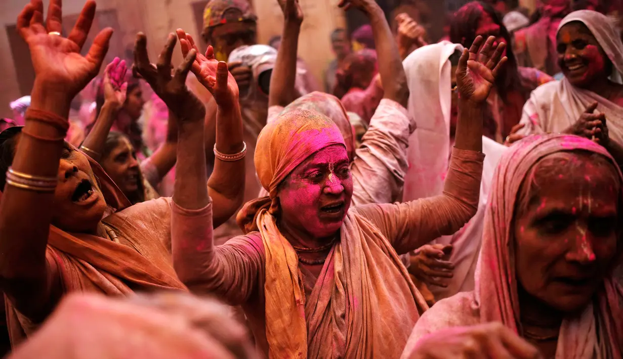 Para janda dengan berlumuran serbuk menari menikmati perayaan Holi di sebuah kuil di Vrindavan, Uttar Pradesh, India (21/3). Holi merupakan salah satu festival perayaan awal musim semi terbesar di India. (REUTERS/Anindito Mukherjee)