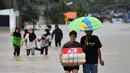 Warga berjalan melewati banjir menyusul hujan lebat di distrik Ran-ngea di provinsi Narathiwat, Thailand selatan (26/2/2022).  Hujan yang disebabkan oleh angin timur laut di atas Teluk Thailand terus berlanjut selama tiga hari berturut-turut di provinsi perbatasan selatan ini. (AFP/Madaree Tohlala)