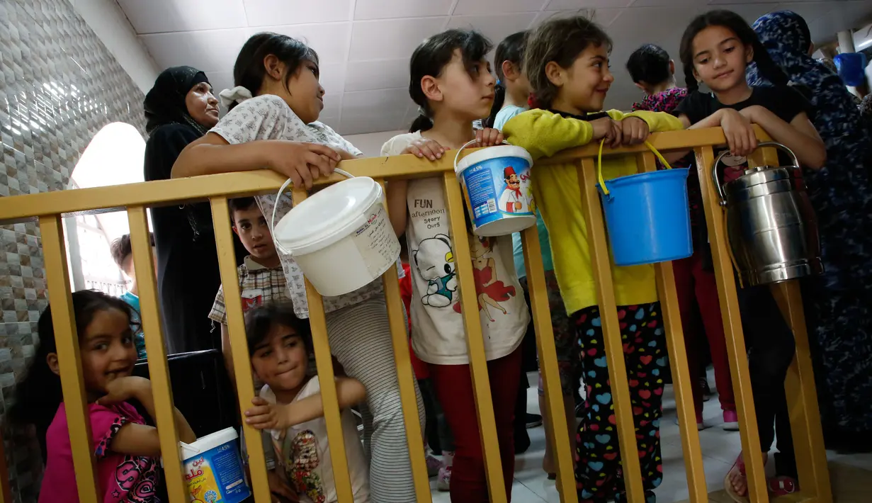 Anak-anak Palestina menunggu untuk mendapatkan makanan buka puasa gratis di sebuah dapur amal, kota Hebron, Tepi Barat, Minggu (20/5). Banyak dari mereka yang mengandalkan makanan gratis karena situasi ekonomi keluarganya yang buruk. (AFP/HAZEM BADER)