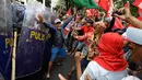 Seorang pria berusaha mencegah bentrokan antara polisi dan demonstran saat aksi di dekat Kedutaan Besar AS di Manila, Filipina (11/11). Mereka menggelar aksi untuk memprotes kunjungan Presiden AS, Donald Trump ke Filipina. (AP Photo/Aaron Favila)