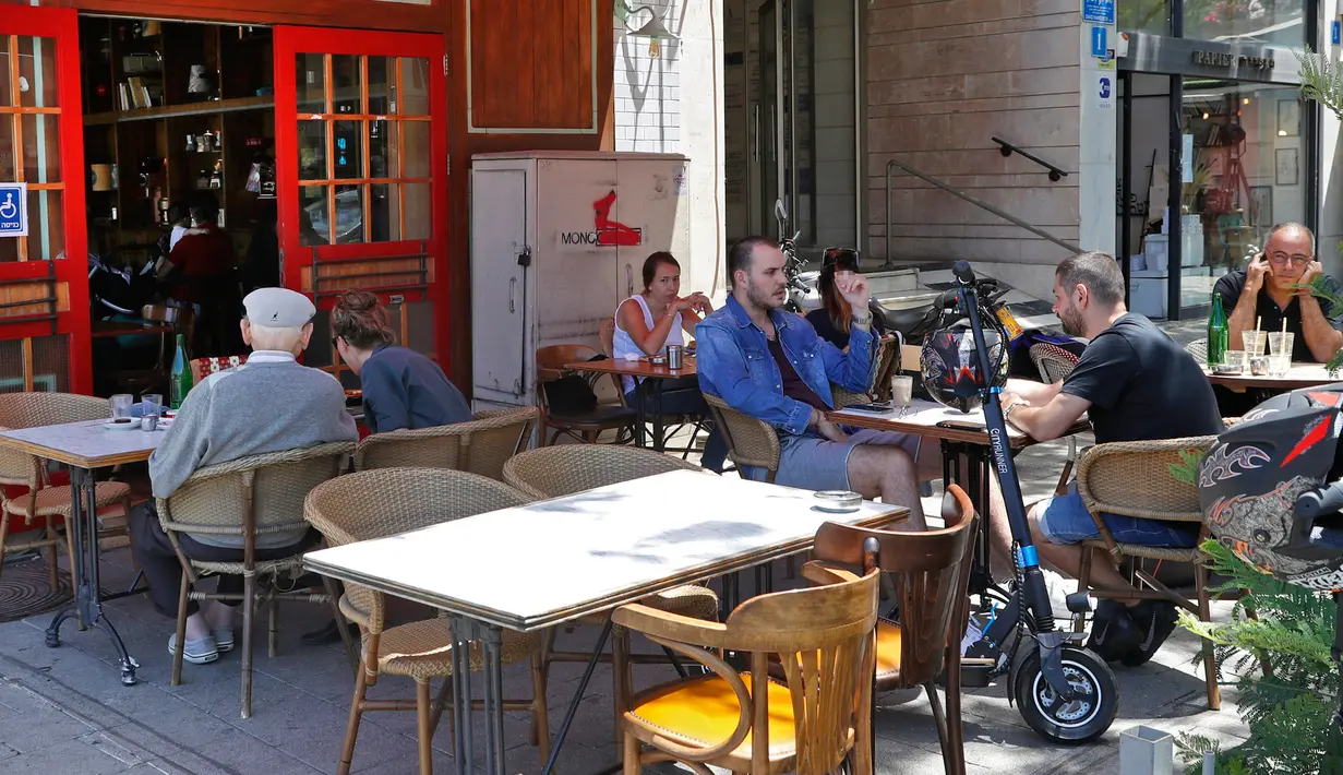 Orang-orang duduk di luar sebuah kafe di kota pantai Mediterania Israel di Tel Aviv, Rabu (27/5/2020). Setelah lebih dari dua bulan, Israel pertama kalinya mengizinkan restoran hingga kafe dibuka kembali usai pelonggaran pembatasan yang diberlakukan untuk mencegah Covid-19. (JACK GUEZ/AFP)