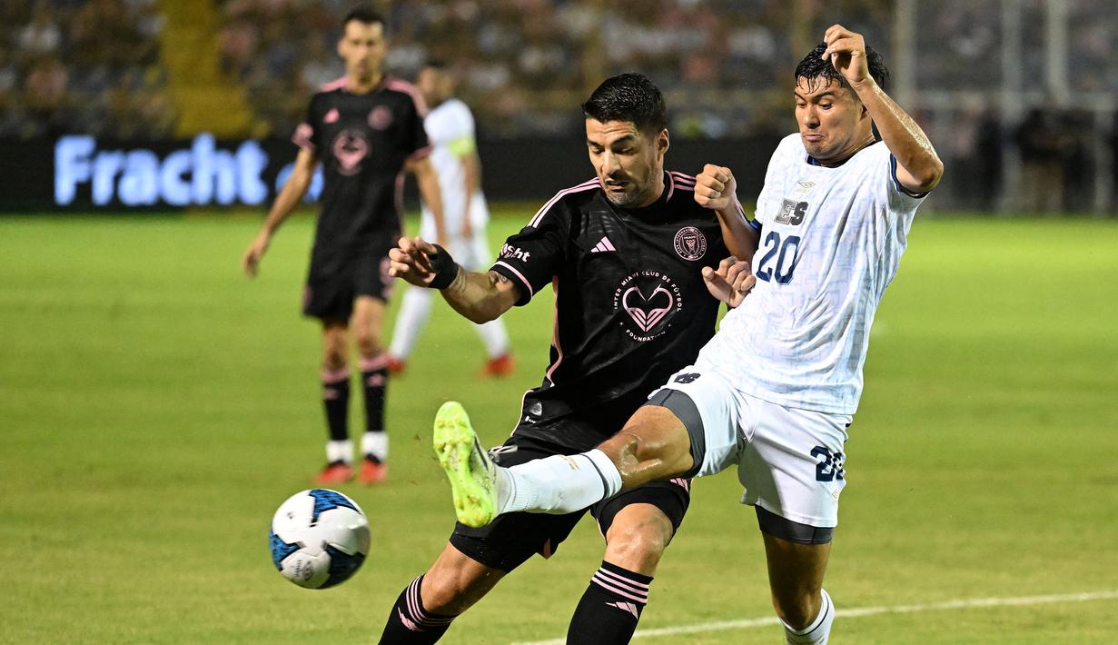 Pemain Inter Miami, Luis Suarez (kiri) berebut bola dengan pemain Timnas El Salvador, Jorge Cruz pada laga persahabatan yang digelar di Kota San Salvador, El Salvador, Sabtu (20/01/2024) pagi WIB. (AFP/Marvin Recinos)