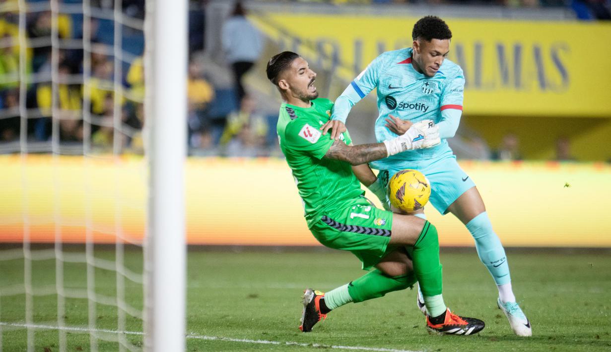 Pemain Barcelona, Vitor Roque, berebut bola dengan kiper Las Palmas pada laga La Liga 2023/2024 jornada 19 di Estadio de Gran Canaria, Jumat (5/1/2024). Barca menang dengan skor tipis 2-1. (AFP/Desiree Martin)