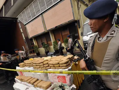 Sejumlah petugas kepolisian mengamankan barang bukti narkoba jenis ganja dan mobil tronton box sebesar dua ton hasil penangkapan ganja Aceh di Polres Jakarta Barat, Jumat (13/2/2015). (Liputan6.com/Faizal Fanani)