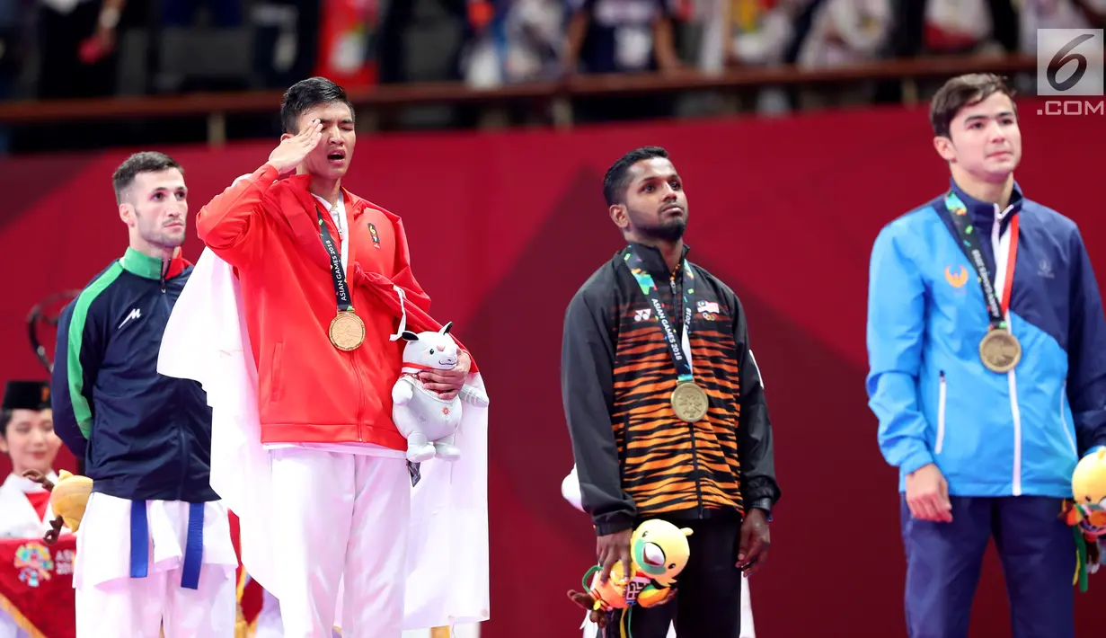 Karateka putra Indonesia, Rifki Ardiansyah Arrosyiid (kedua kiri) menyanyikan lagu Indonesia Raya usai meraih medali emas di babak final nomor Kumite -60 kg di Arena Karate JCC Senayan, Jakarta, Minggu (26/8). Liputan6.com/Fery Pradolo)