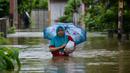 Seorang perempuan melintasi lingkungan yang banjir setelah tiga hari diguyur hujan lebat di Banda Aceh, Aceh, Sabtu (9/5/2020). Banjir akibat intensitas hujan tinggi tersebut mengakibatkan sebagian besar kawasan di ibu kota Provinsi Aceh ini digenangi air. (Photo by CHAIDEER MAHYUDDIN/AFP)