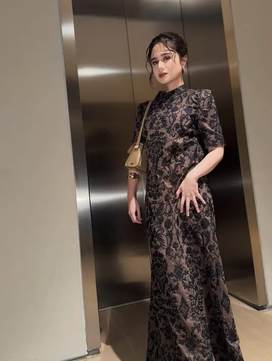 <p>Tissa Biani mengenakan long dress embroidery hitam kerah tinggi dipadukan shoulder bag warna nude. [@tissabiani]</p>