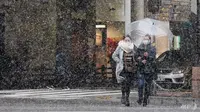 Pejalan kaki berjalan di jalan saat salju turun di Fukuoka pada 30 Des 2020. (Foto: AFP / Jiji Press)