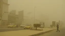 Seorang pria melintasi jalan utama selama badai pasir Musim Semi di ibukota Irak, Baghdad (5/5/2022). Irak dihantam oleh serangkaian badai semacam itu pada bulan April, menghentikan penerbangan dan membuat puluhan orang dirawat di rumah sakit karena masalah pernapasan. (AFP/Sabah Arar)