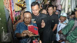 Sejumlah warga berebut untuk berfoto bareng dengan Cagub DKI Jakarta Agus Harimurti Yudhoyono di Pasar Senen, Jakarta, Selasa (8/11). Selain meminta doa dan dukungan, Agus juga mendengarkan keluhan para pedagang Pasar Senen. (Liputan6.com/Yoppy Renato)