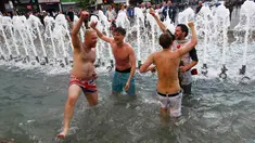 Sejumlah suporter Inggris bernyanyi merayakan kemenangan Timnas Inggris di kolam air mancur yang berada di tengah Kota Lille, Prancis (16/6). Aksi suporter Inggris menjadi tontonan warga yang melintasi kawasan tersebut. (REUTERS / Wolfgang Rattay)