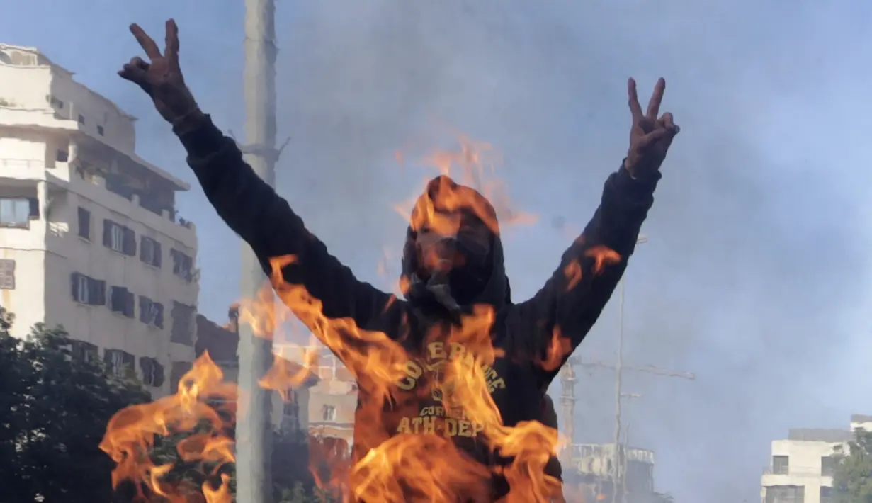 Demonstran antipemerintah meneriakkan slogan-slogan dekat kobaran api saat protes menentang elite penguasa di Kota Jal el-Dib, Lebanon, Selasa (14/1/2020). Demonstran menganggap elite penguasa gagal mengatasi ekonomi yang menurun tajam. (AP Photo/Hassan Ammar)