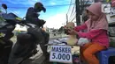 Seorang ibu ditemani anaknya melayani pembeli saat berjualan masker kain buatan rumahan di Jalan Raya Cinere-Depok, Limo, Depok, Rabu (8/4/2020).  Anjuran pemerintah mengenai penggunaan masker kain dimanfaatkan ibu ini untuk berjualan masker kain. (merdeka.com/Arie Basuki)