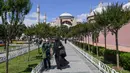Orang-orang berjalan di depan Hagia Sophia di Istanbul, Turki pada 11 Juli 2020. Hagia Sophia, bangunan berusia 1.500 tahun, saat ini berubah statusnya menjadi masjid. (Ozan KOSE/AFP)