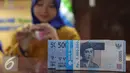 Teller menghitung uang rupiah di Bank Bukopin Syariah, Jakarta, Selasa (29/12). Rupiah kembali melemah, di tengah sepinya transaksi jelang libur Tahun Baru Hingga akhir pekan, pergerakan rupiah diperkirakan masih terbatas. (Liputan6.com/Angga Yuniar)