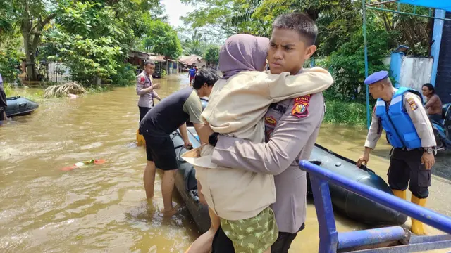 Personel Direktorat Polisi Air dan Udara Polda Riau menggendong wanita lansia yang menjadi korban banjir di Pekanbaru.
